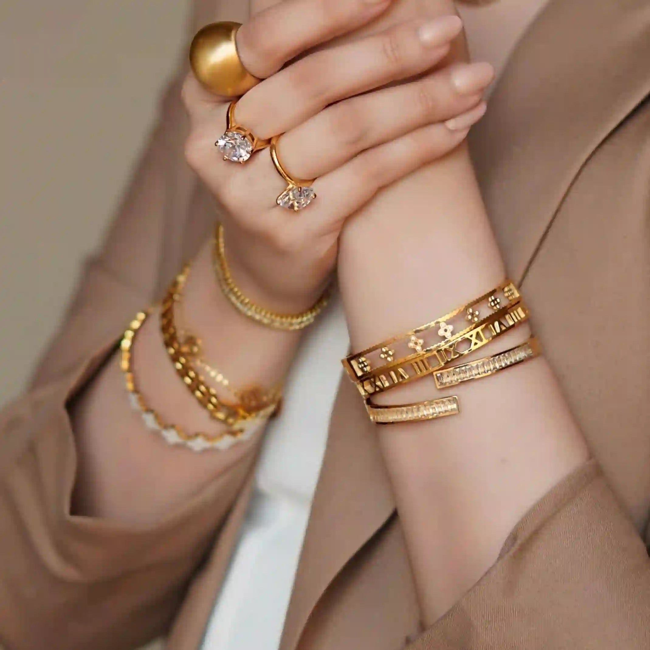 Closeup of girl wearing gold plated bracelets and rings in both hands.