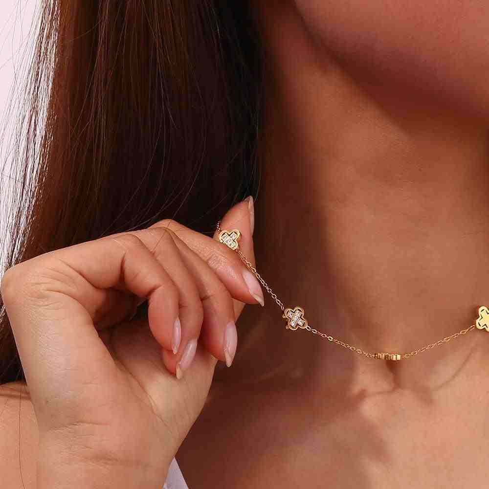 celebrity wearing gilded clover necklace from mithra and co and holding it in her right hand.