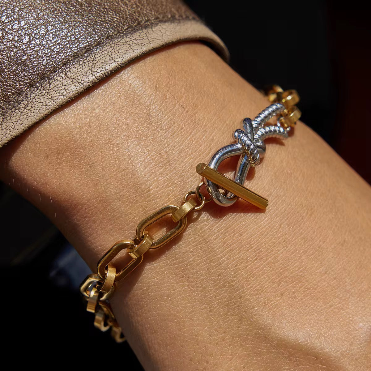 Gold and silver bracelet on a wrist with a dark background