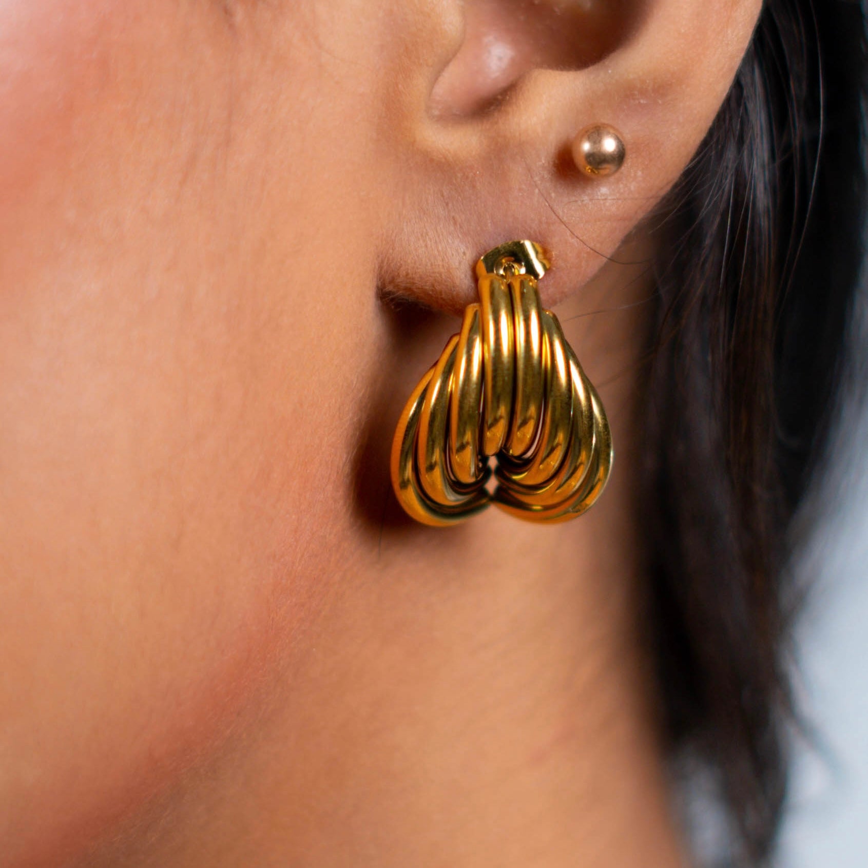 Gold earring worn by a person with a blurred background