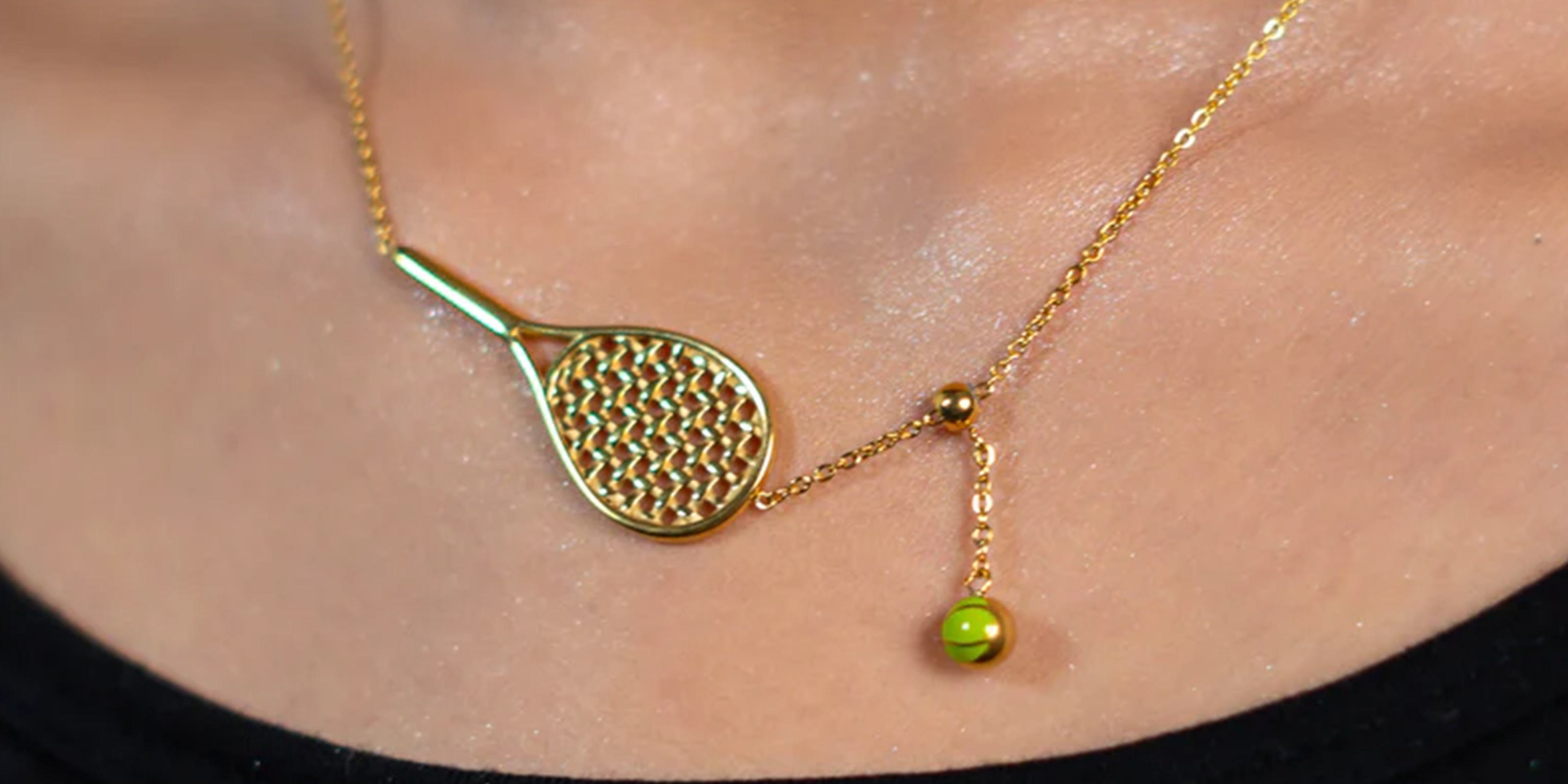 NeckPieces Collection Showcasing close up of girl wearing gold plated necklace with tennis racket and ball pendant on skin.