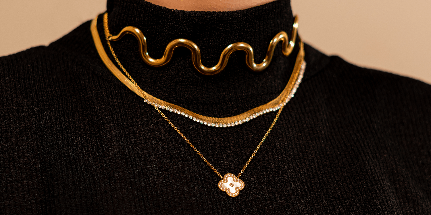 Woman wearing Gold Plated Necklaces on a black turtleneck against a beige background. Shop Online Pakistan.