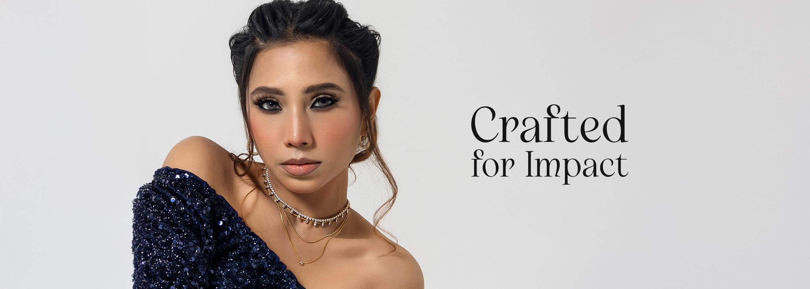 Woman wearing a dark blue dress with artificial jewelry sparkling effect on a light gray background, with text 'Crafted for Impact' displayed.