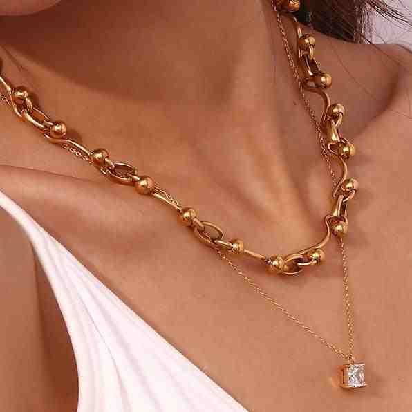 Close-up of woman wearing 18k Gold Plated aristo necklace and crushed ice square necklace. Minimalist Chain and a Bold necklace