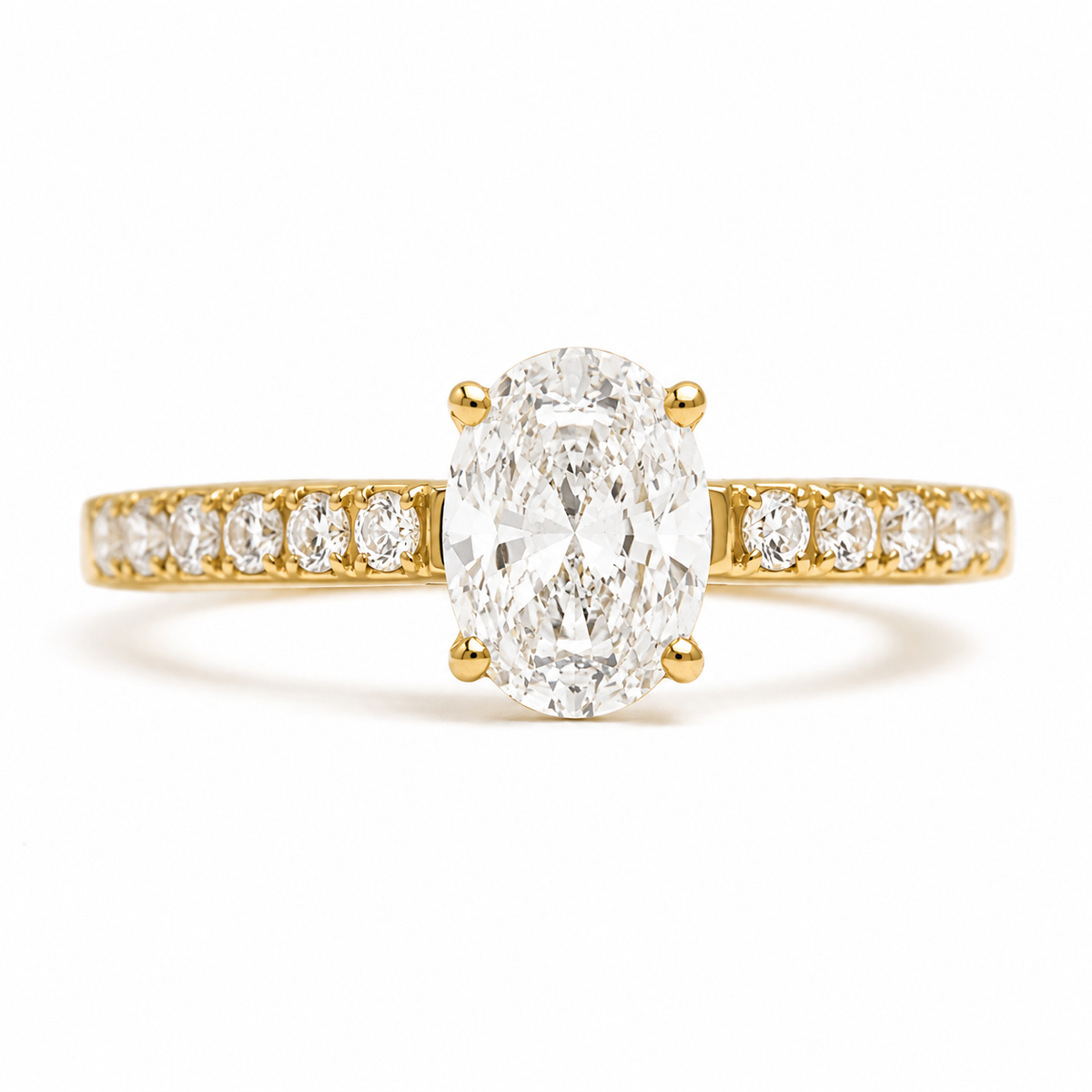 A yellow gold engagement ring featuring a large oval-cut center diamond set in a four-prong setting, with a pavé band lined with smaller round diamonds, shown on a clean white background.