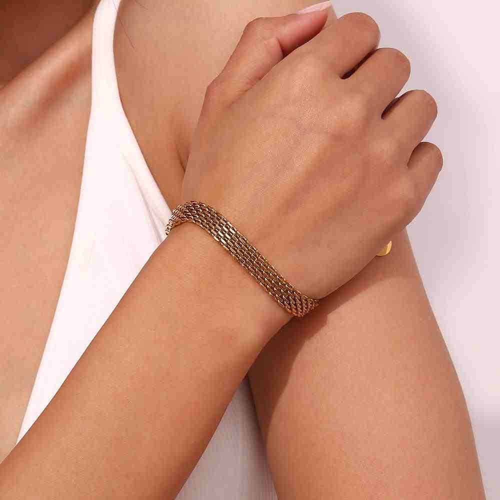 Model's wrist wearing 18k Gold Plated woven mesh Rowena bracelet with hand resting on the shoulder, highlighting the bold gold statement.
