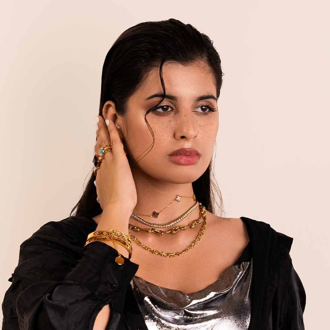 Woman wearing gold jewelry on a beige background