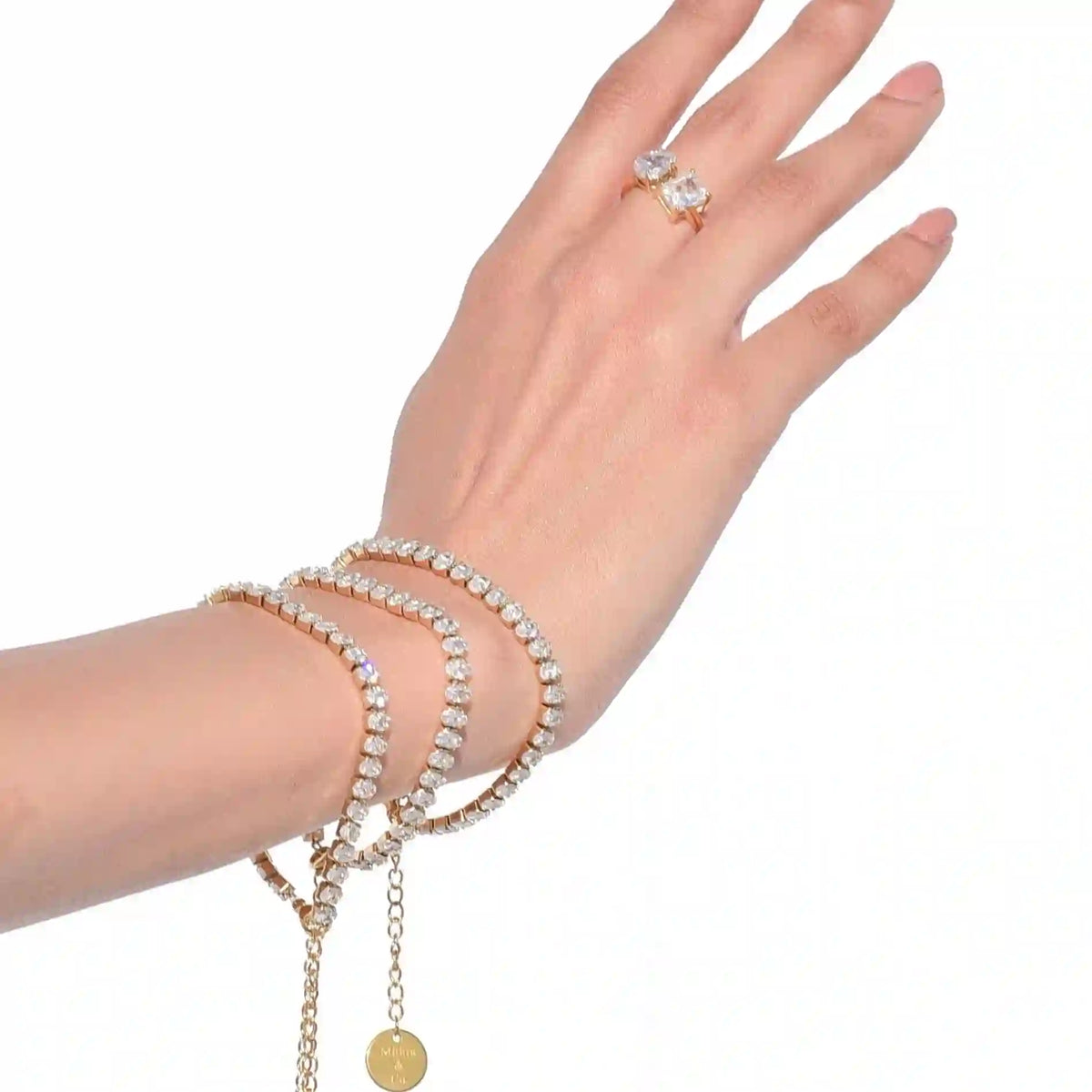 Closeup of a girl's hand wearing 3 linea diamond cut bracelets stacked. 18k Gold Plated tennis bracelet with diamond cut zircons.