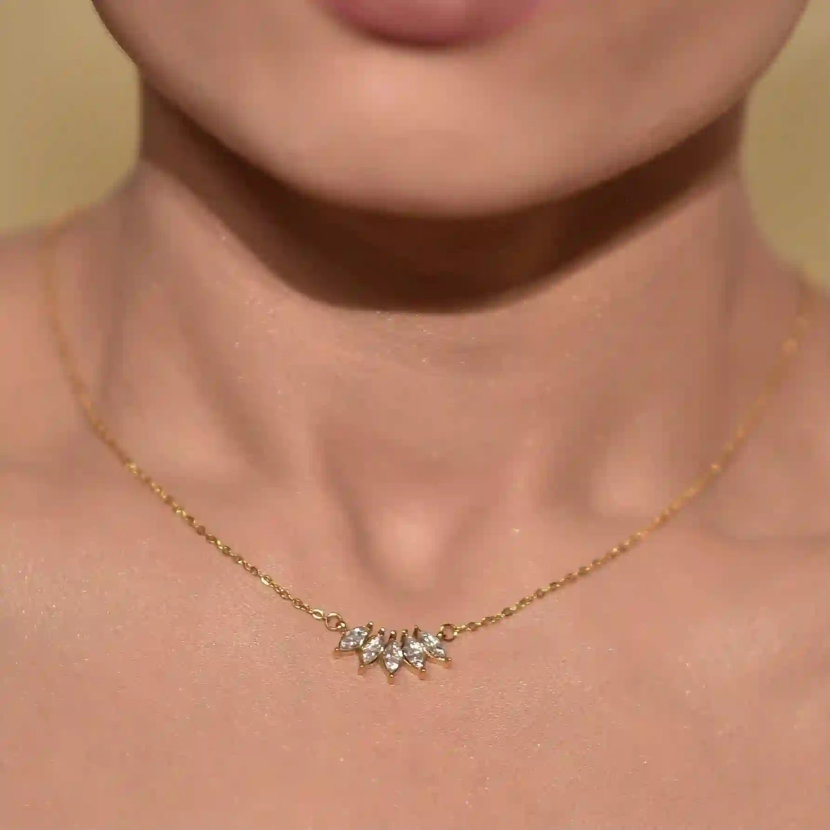 Closeup of a GIrl neck wearing gold plated necklace with 4 rhombus shaped zircons pendant on against a neutral background