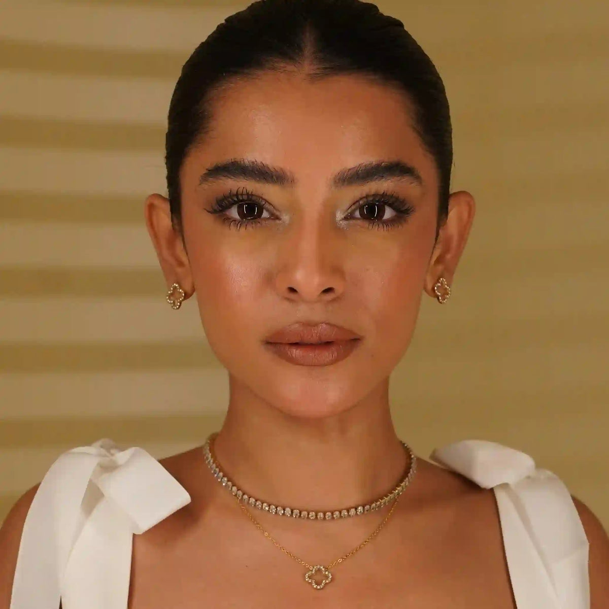 front view of a woman wearing linea tennis necklace with hollow clover studded necklace.
