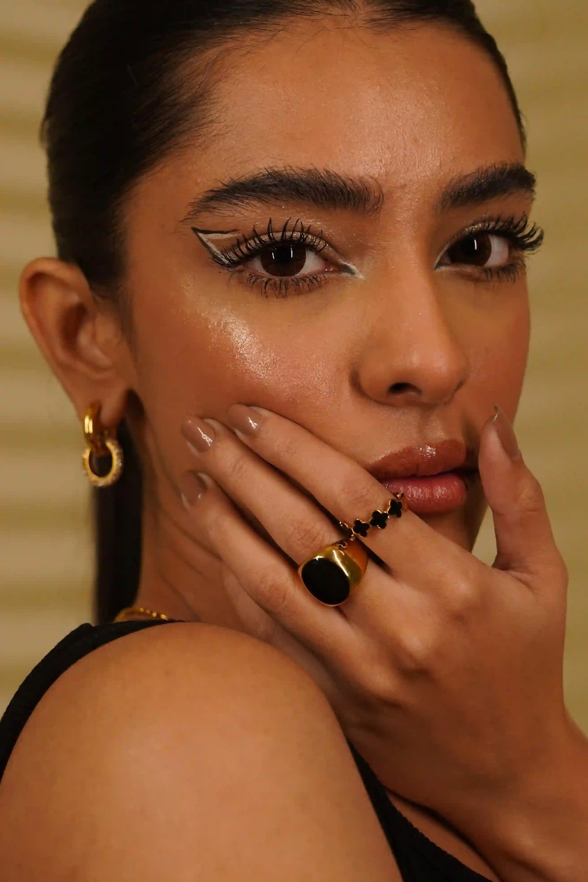 Closeup of a girl wearing gold plated necklaces, earrings, bracelets and rings including malachite black ring and clover black band ring.