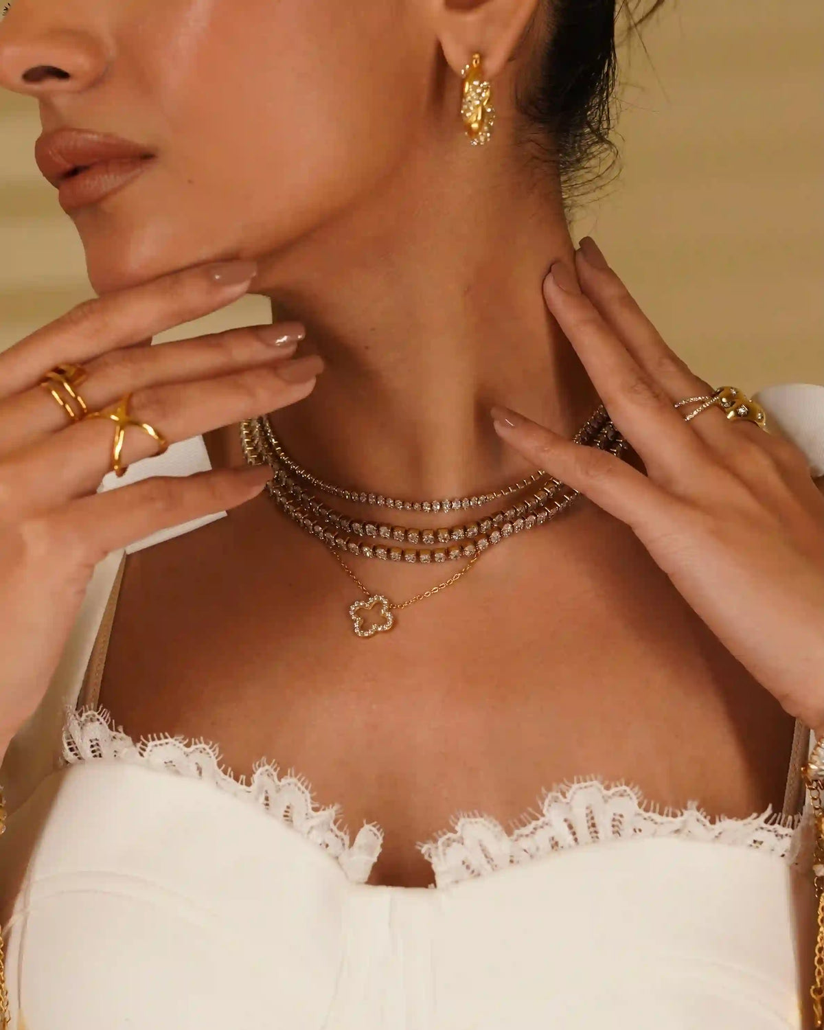 Closeup of a Woman Stacking Gold Plated jewelry with Hollow clvoer studded necklace having Pave Zircon Layering on an Open-Work Quatrefoil.