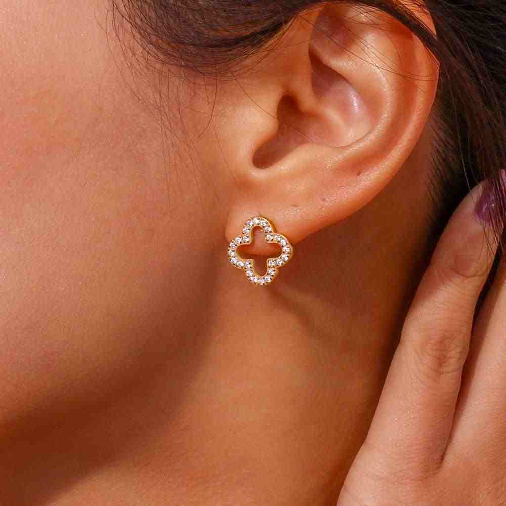 Closeup of a Woman's left ear wearing hollow clover studded studs.