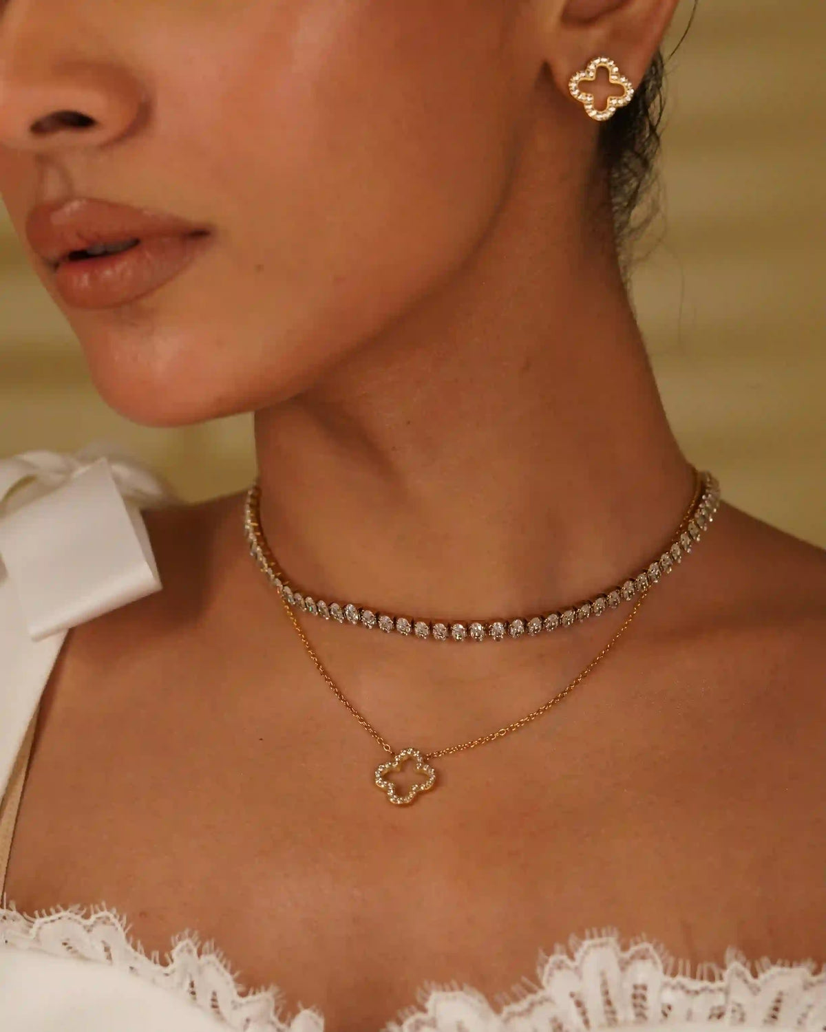 Closeup of a woman wearing Linea Necklace stacking with Hollow Clover Studded Neckalce and Studs. Pave Zircon Layering on a Hollow Quatrefoil.