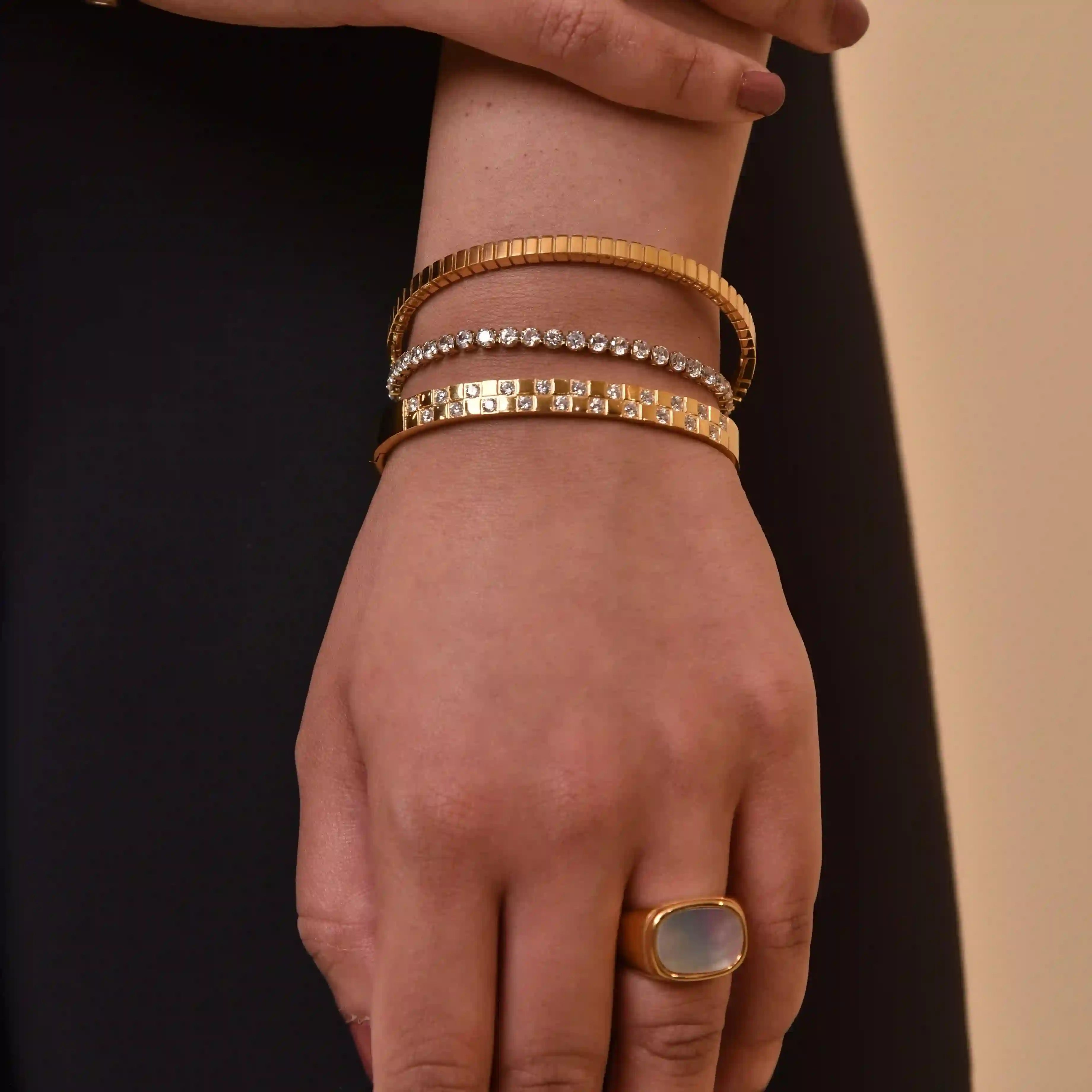 Woman wearing 18k Gold Plated bracelets with rhinestones and a gold ring with a stone