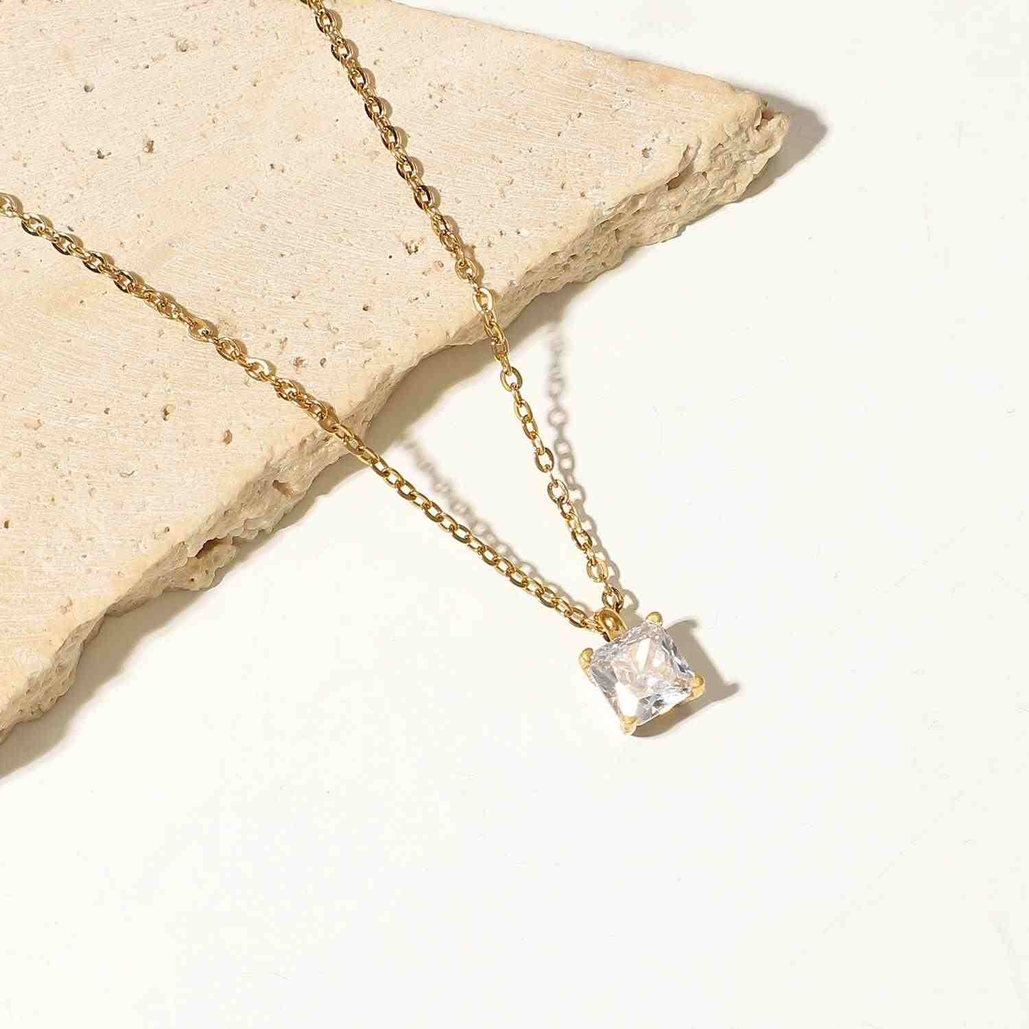 18k Gold Plated necklace with square clear gemstone pendant on textured surface