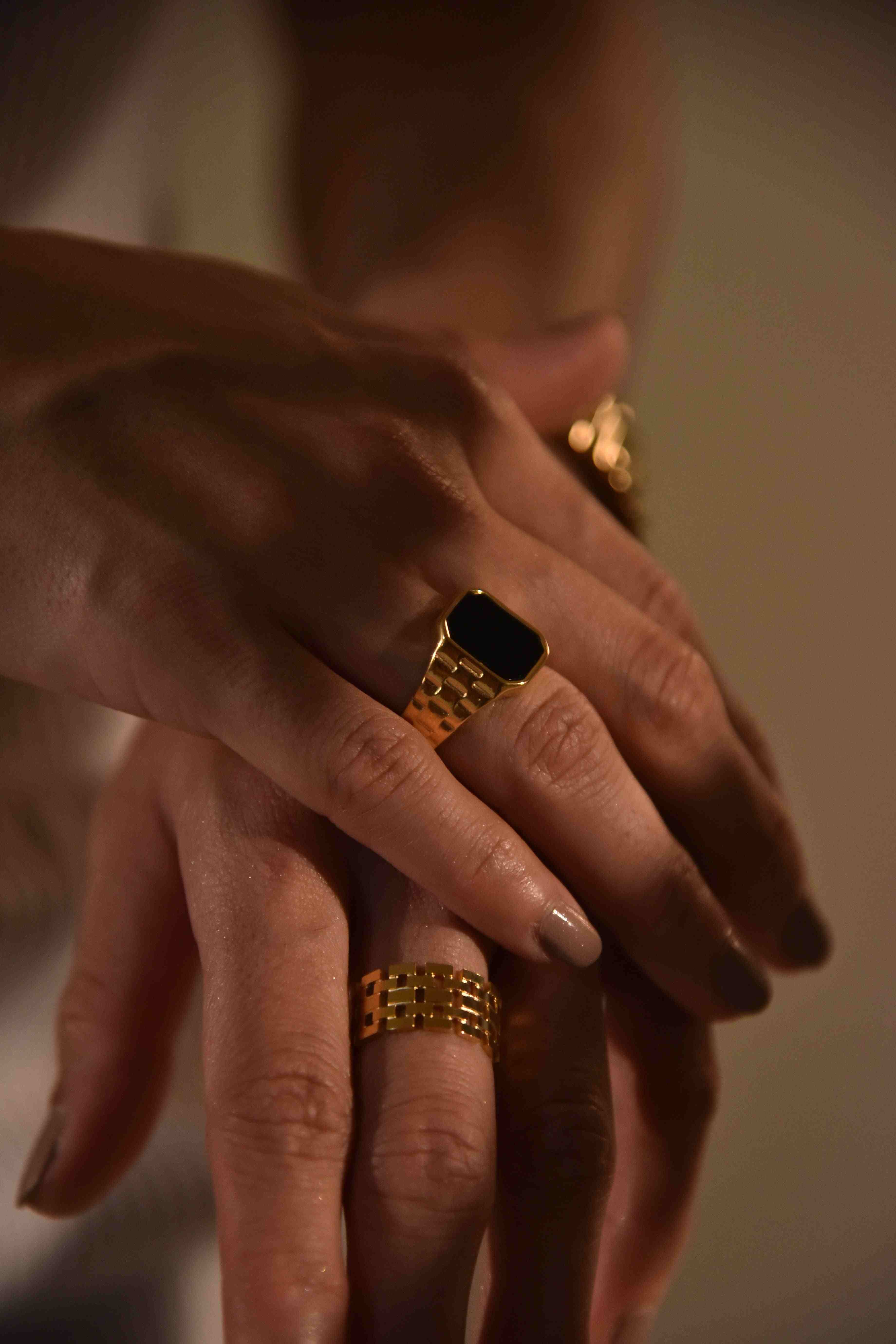 woman wearing 18k Gold Plated black stone signet ring and linked gold band ring on fingers
