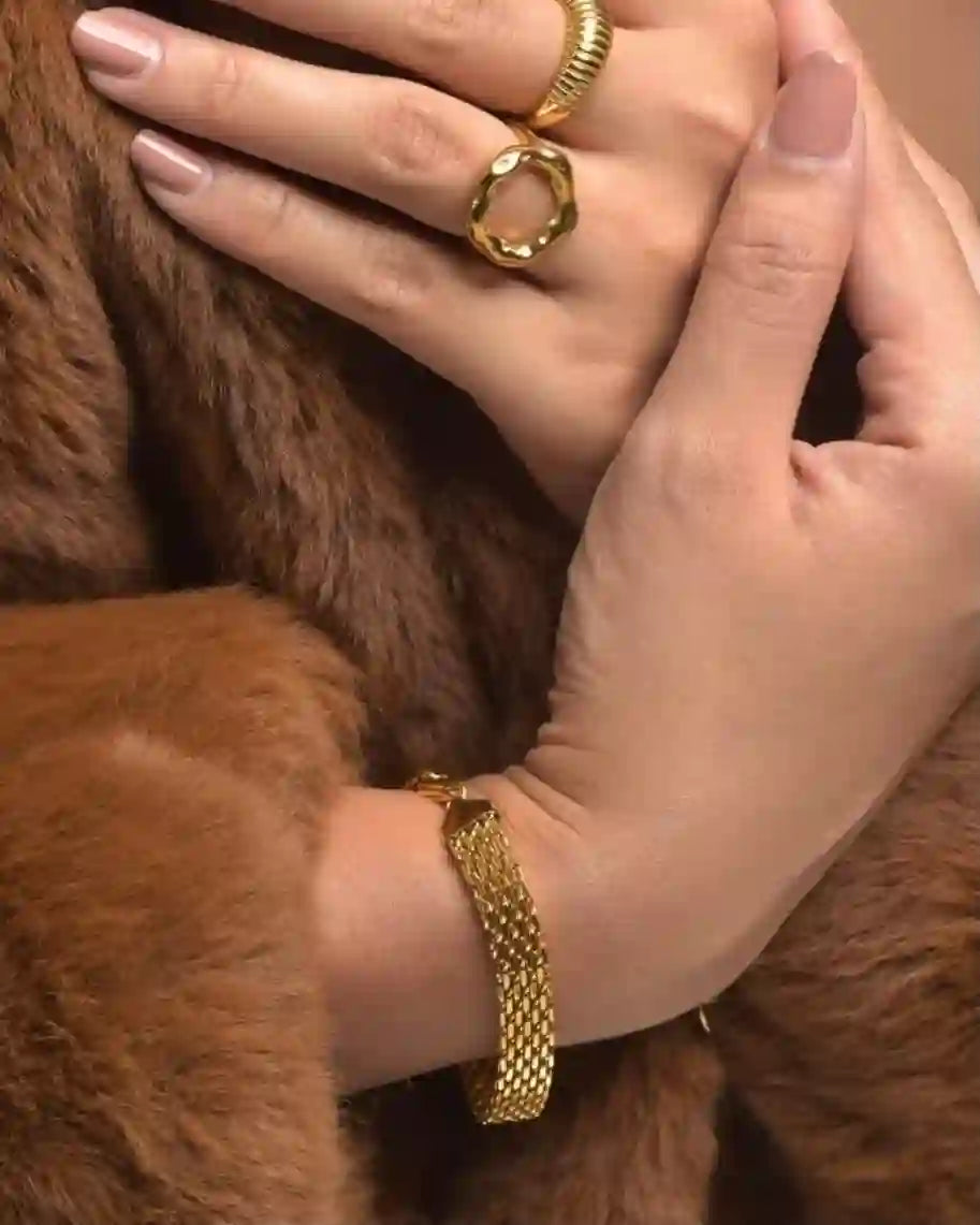 Two hands clasped together, with the wrist wearing the Gold Plated woven Mesh design Rowena bracelet prominently displayed.