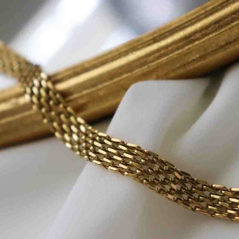 Llinks of Rowena gold plated watch bracelet: Open view of Rowena bracelet clasp and straightened links resting on white fabric next to a simple bangle.