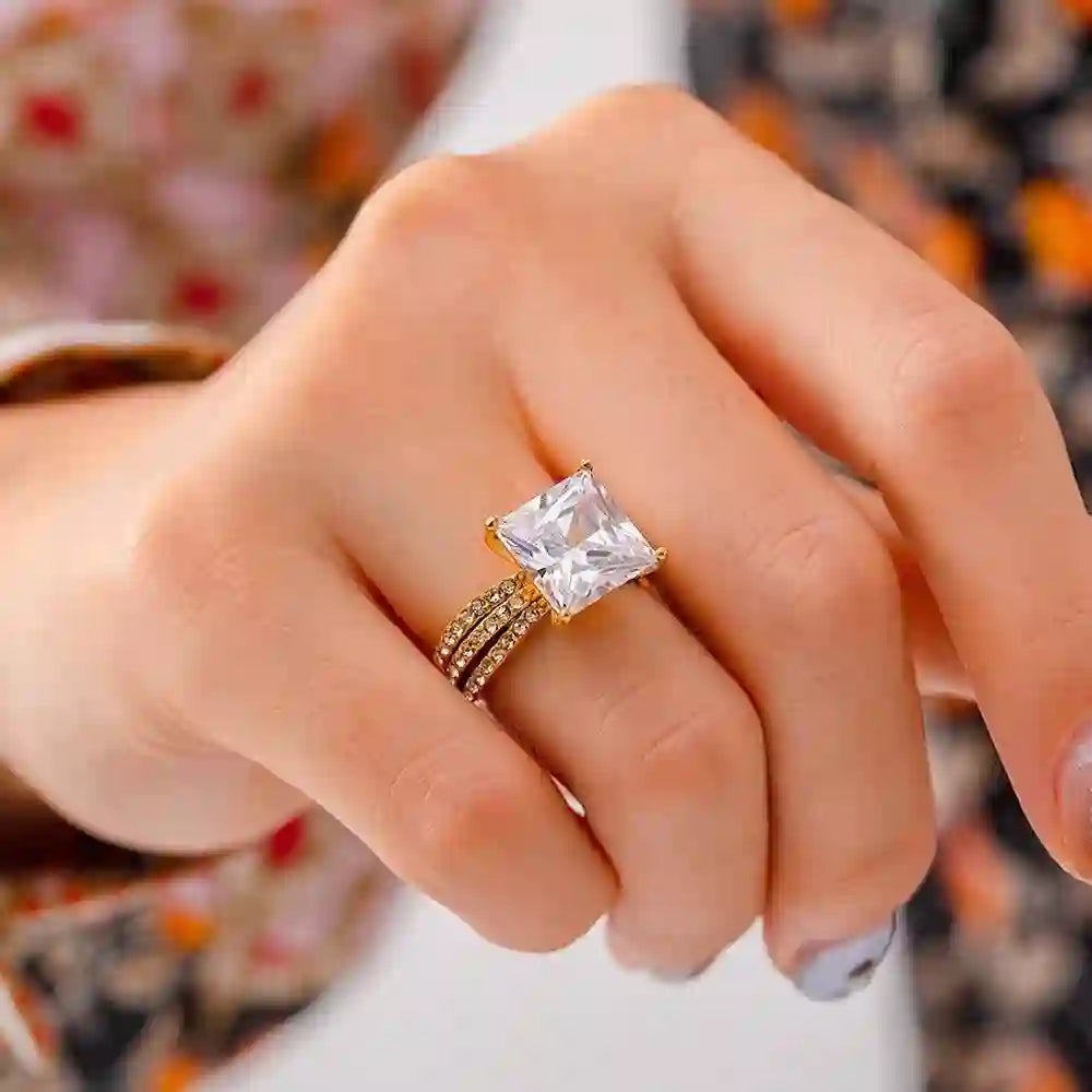Closeup of a girl's hand wearing 18k Gold plated Aura Zircon triple row pave band ring with large square Centerpiece and 3 rows studded with micro zircons.