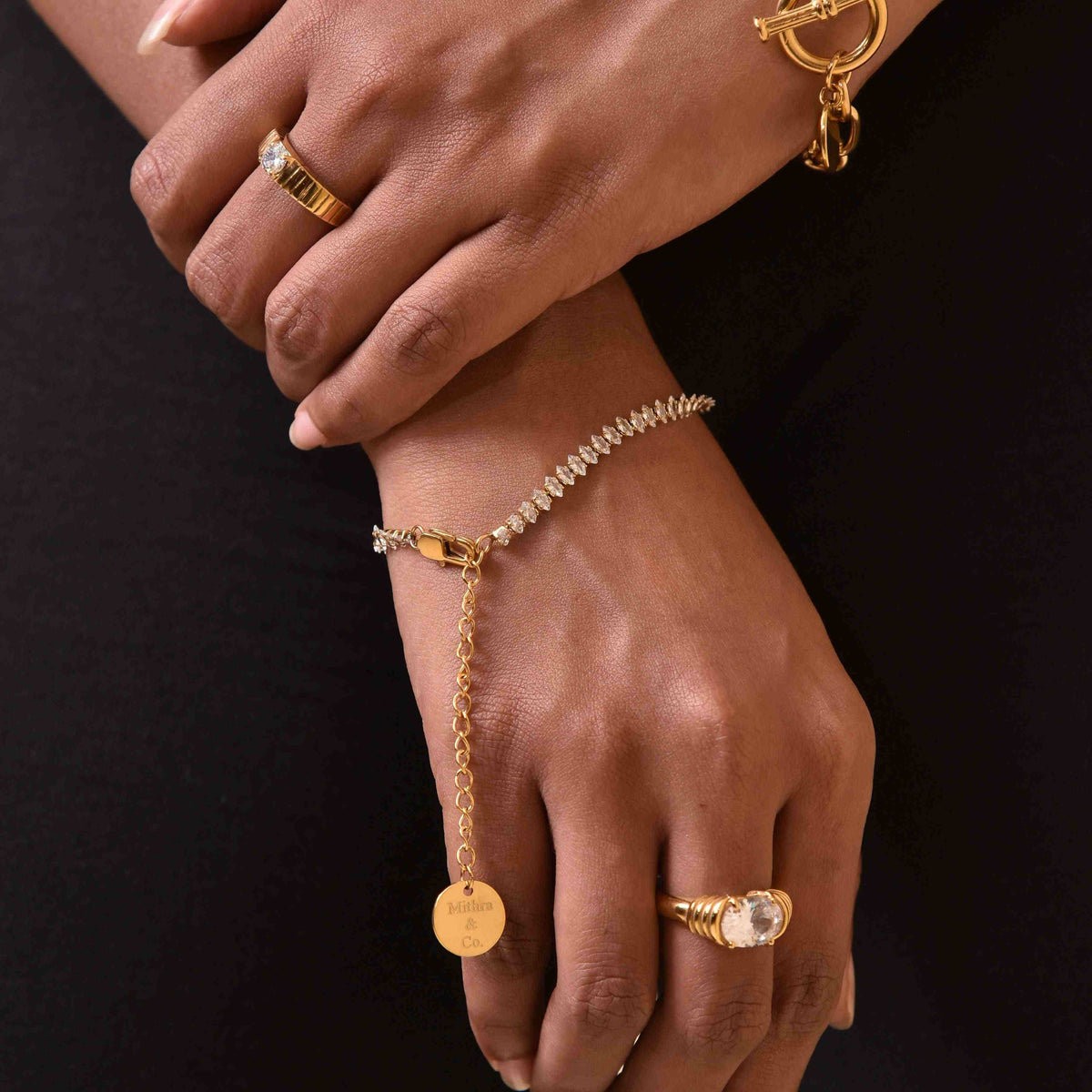 closeup of both hands wearing 18k GOld Plated Bowie Ring and tennis bracelet with another ring.