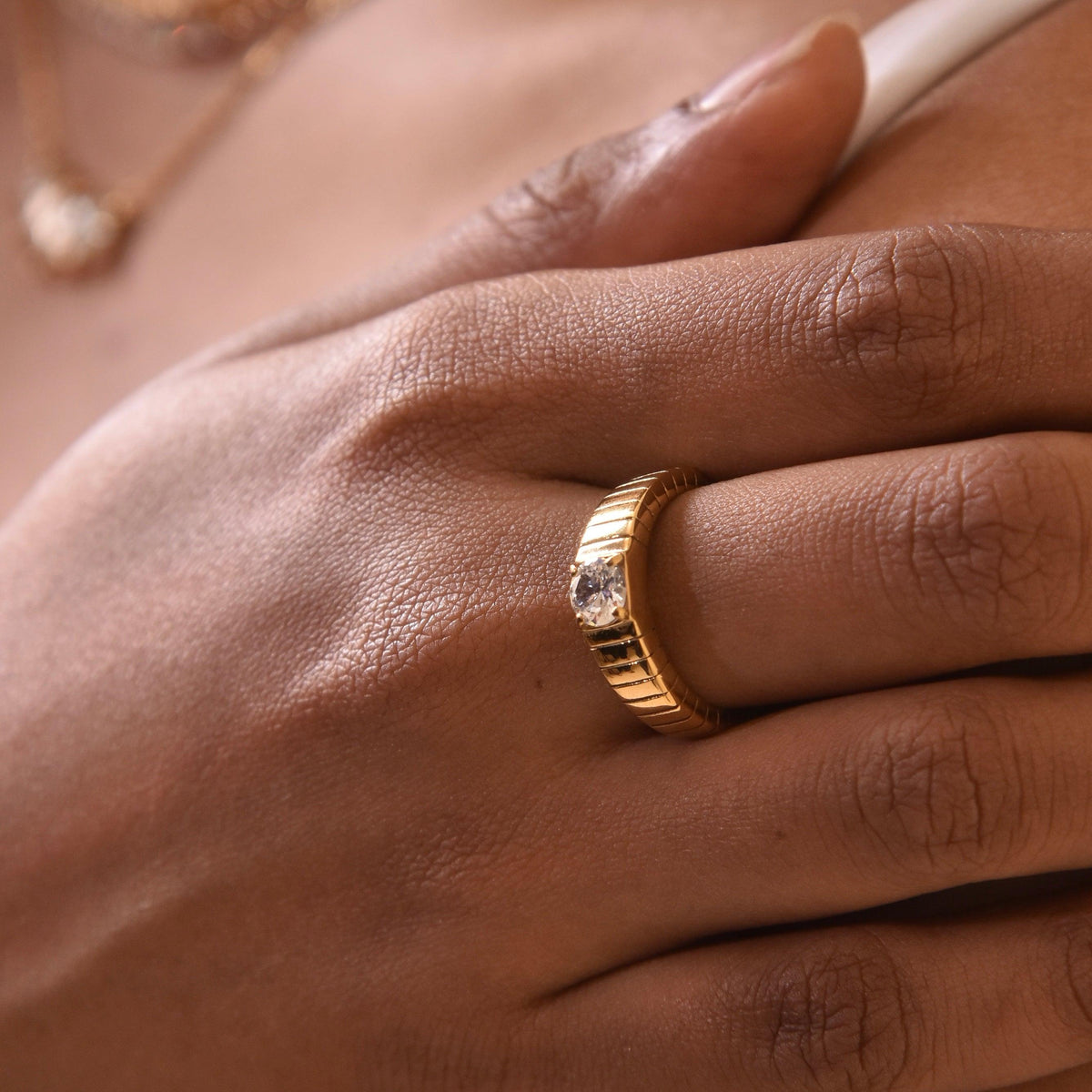 Closeup of hand wearing bowie ring - industrial-style groove etched Cubic Zirconia Gold ring. Shop Online at Mithra and Co.