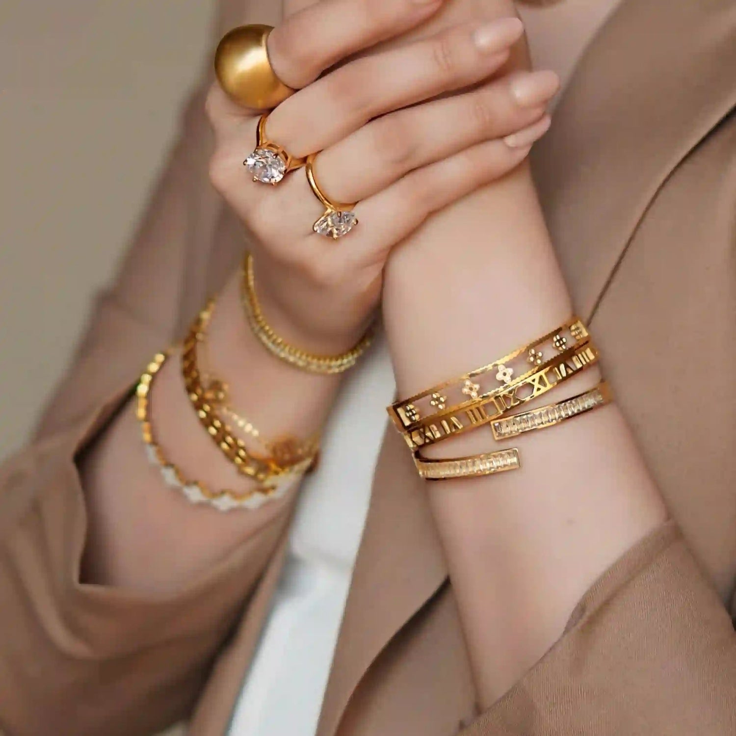 Closeup of girl wearing gold plated bracelets and rings in both hands.