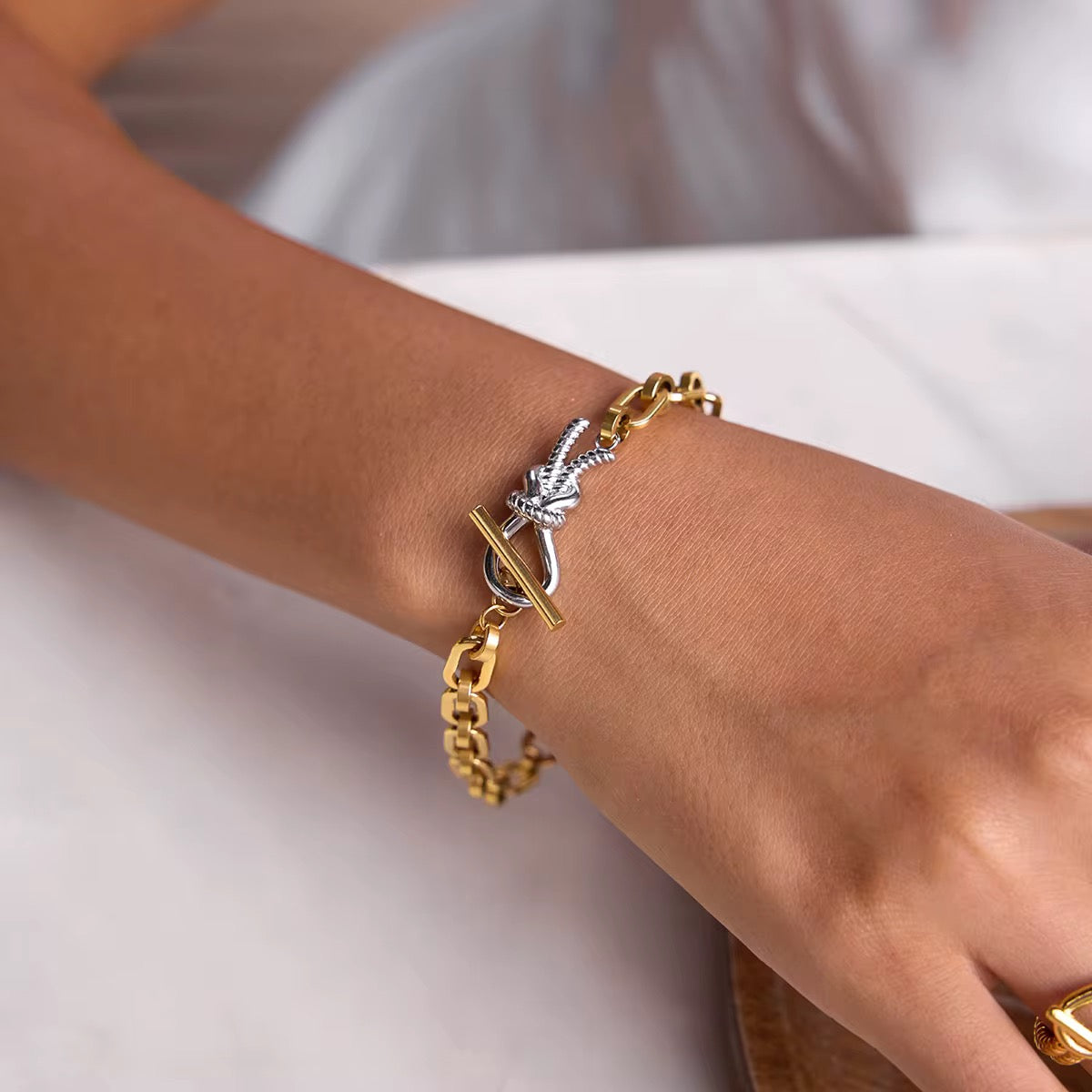 Gold and silver bracelet on a wrist against a neutral background