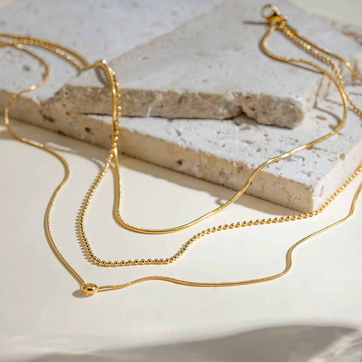 Gold necklaces on a textured stone surface