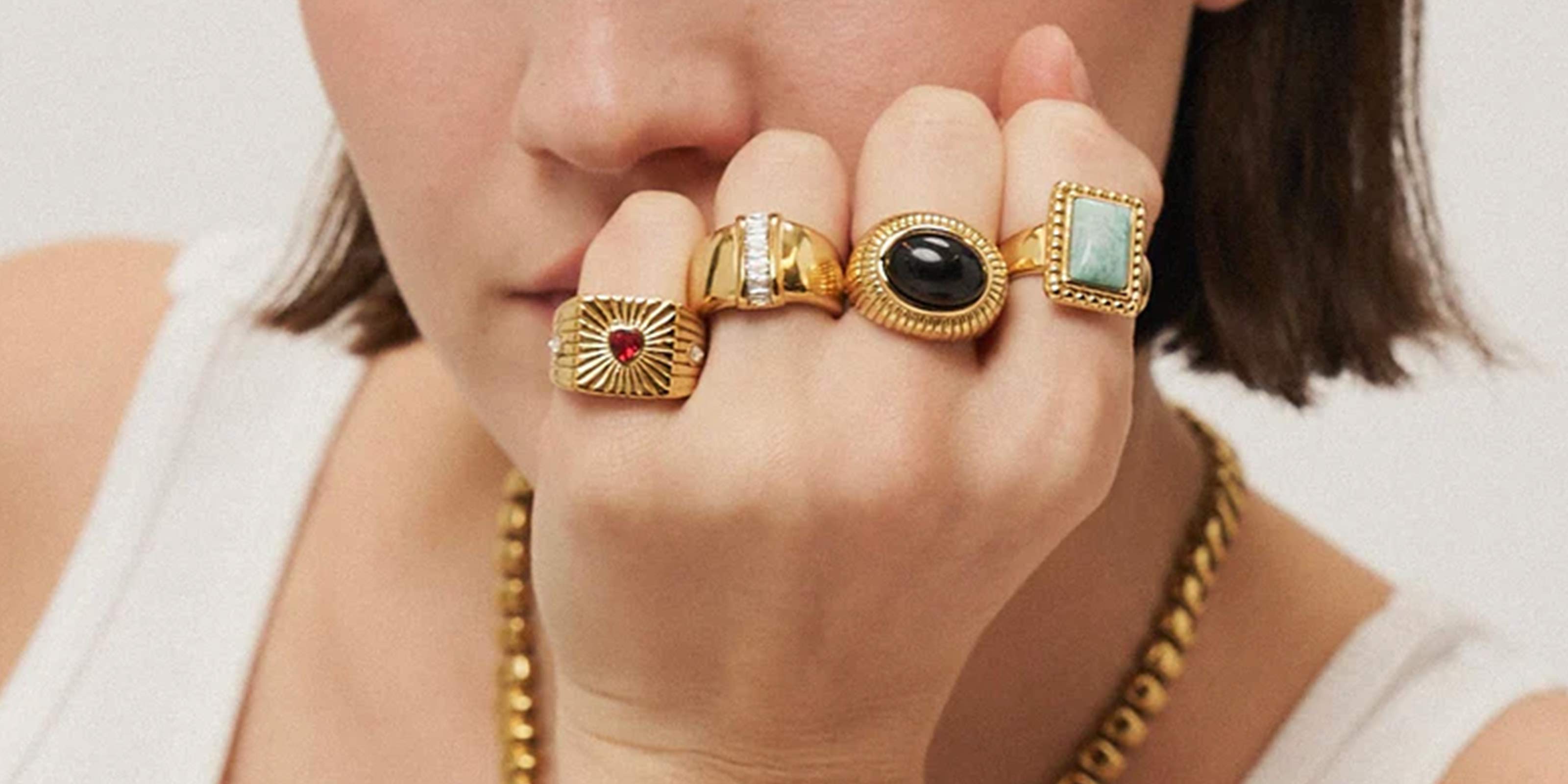 The Alchemy Collection Showcasing Close-up of a girl wearing gold rings with gemstones on a neutral background