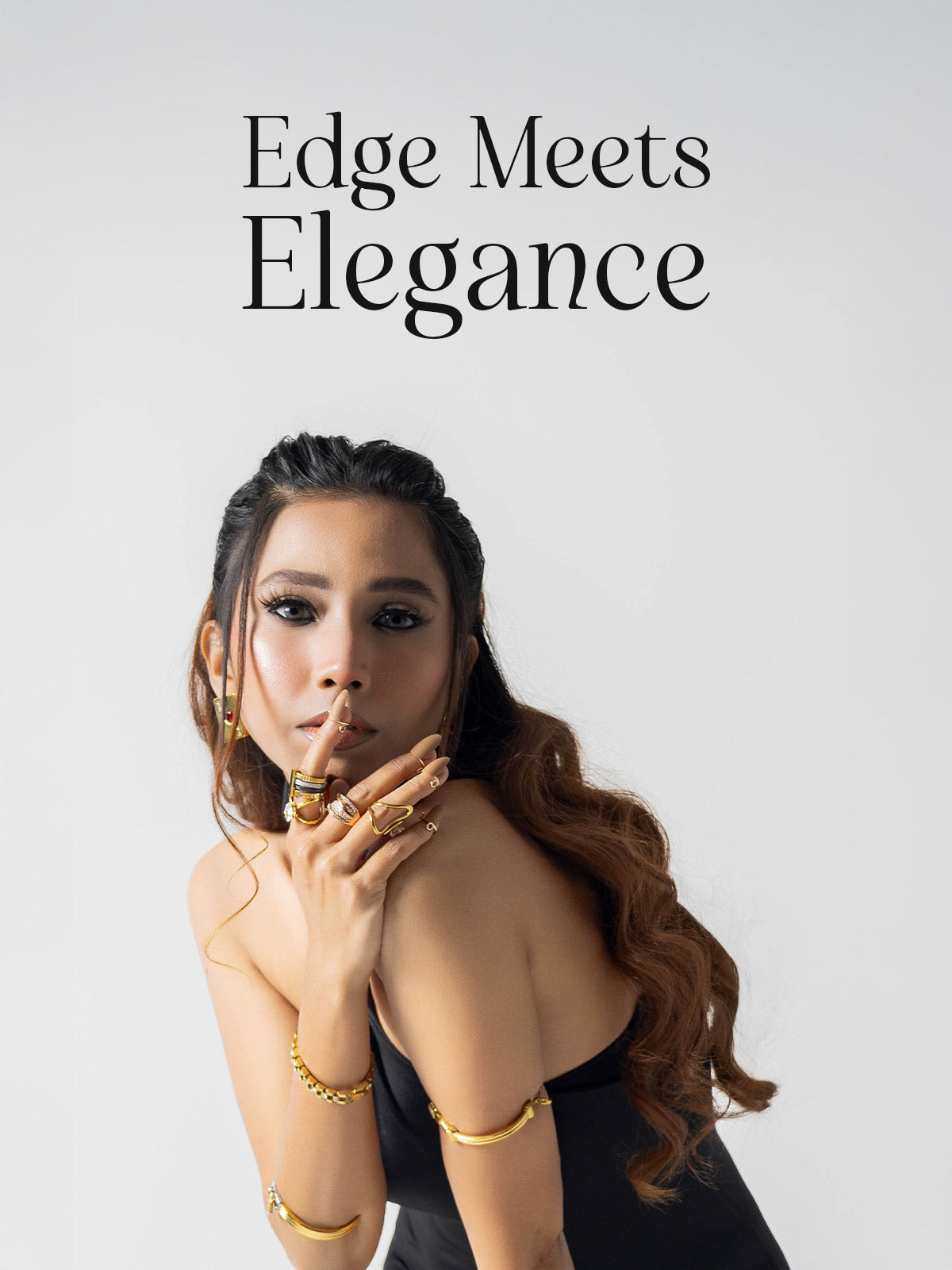 Woman with styled hair wearing gold plated jewelry against a plain background with 'Edge Meets Elegance' text above.