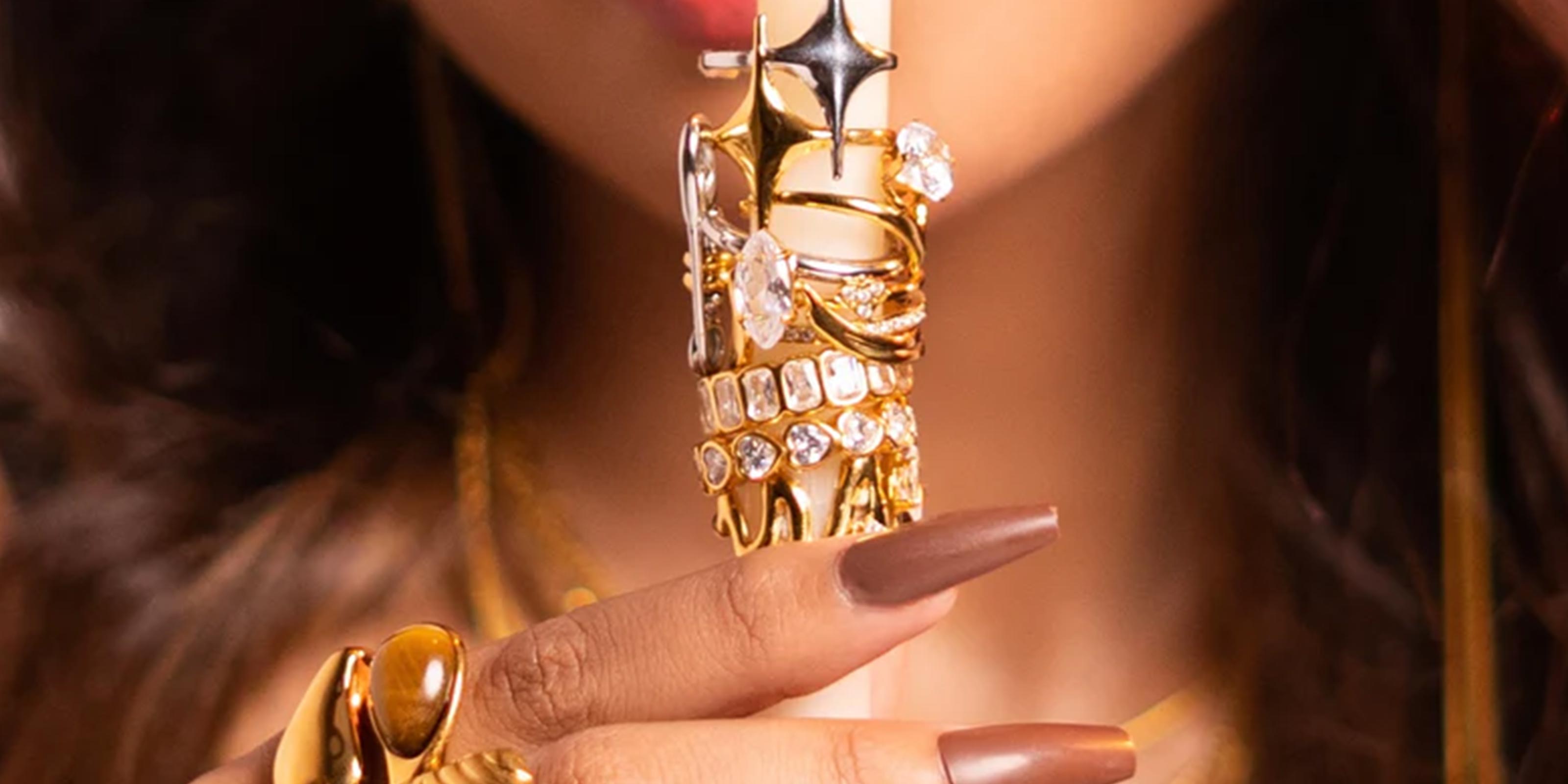18k GP Rings Collection SHowcasing Close-up of a Girl's hand holding a candle with rings on it.