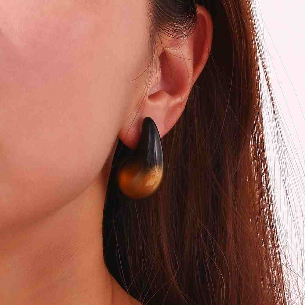 Closeup of a Girl's Left ear wearing Avant Garde Earrings with Sculptural Black and Gold Ombre Teardrop design. Shop at Mithra and Co.