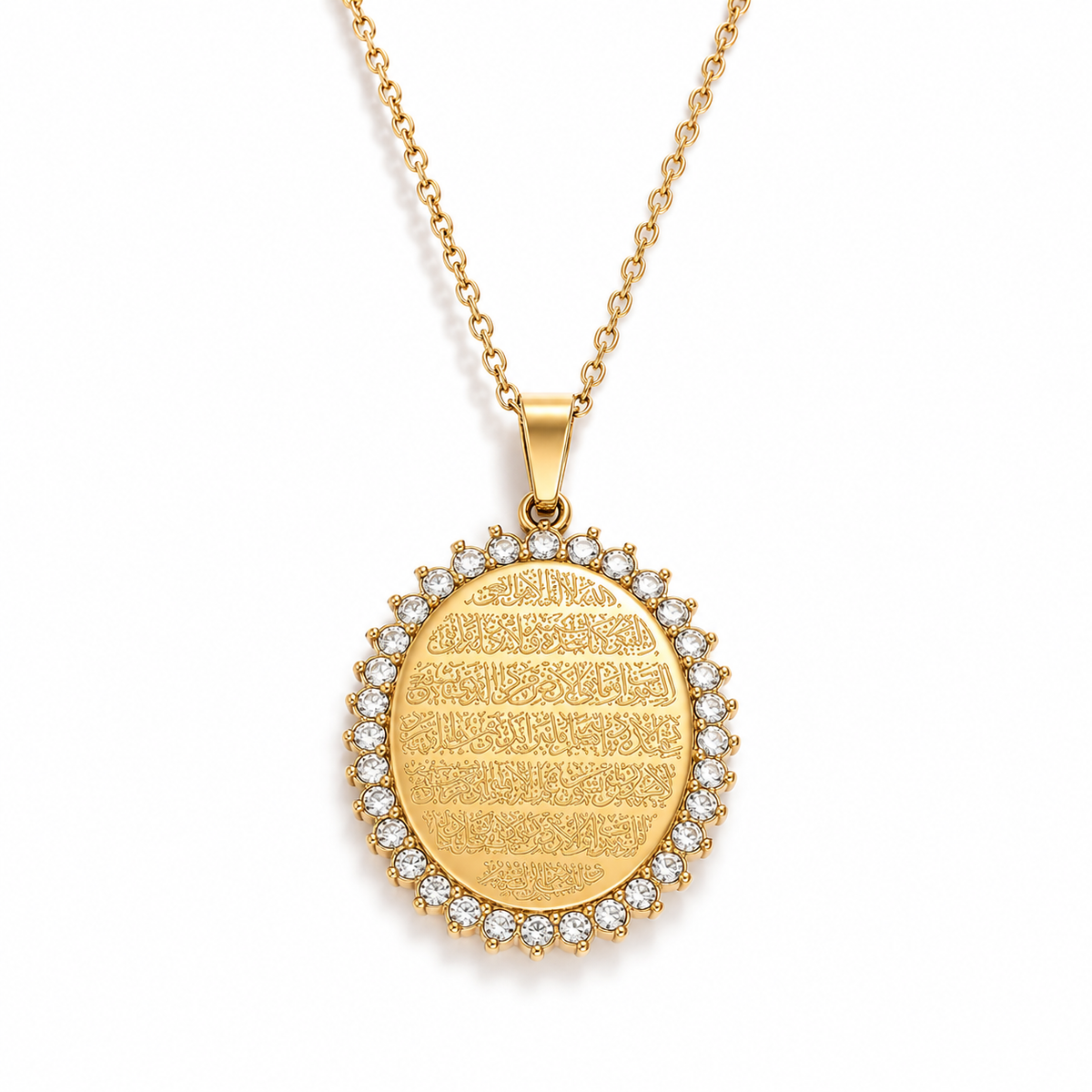 Ayatul kursi locket. An oval gold plated arabic pendant necklace featuring engraved Arabic calligraphy and a border of small clear stones, shown on a white bg.
