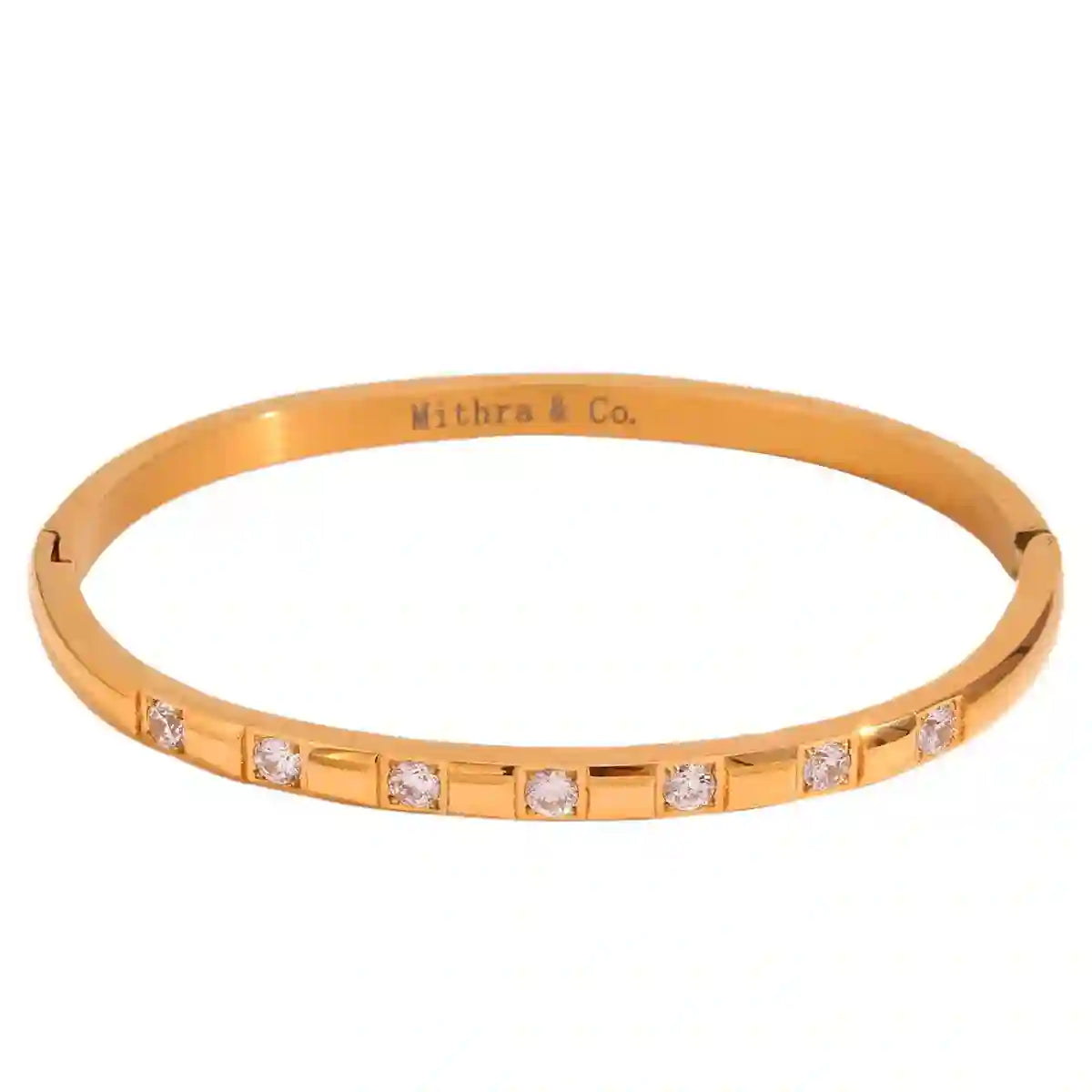 Studio shot of claro coff. 18k pvd gold plated bangle with round cut zircons and Mithra & Co. Engraved inside.