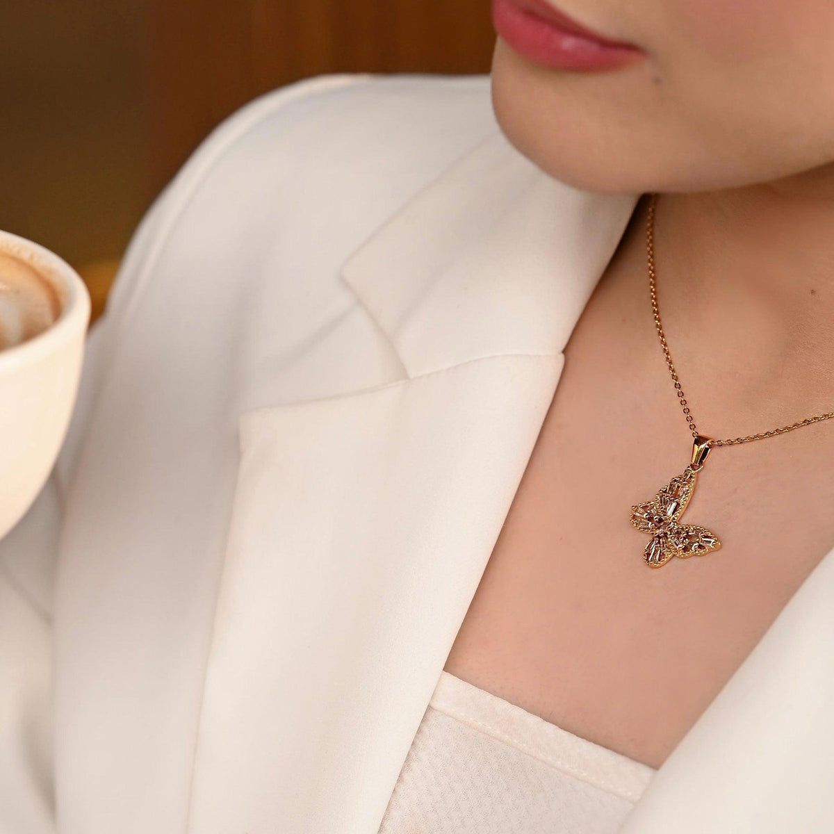 Girl wearing White blazer and 18k Gold plated Enchanted Flutter Necklace having butterfly motif with Segmented Baguette Zircons.