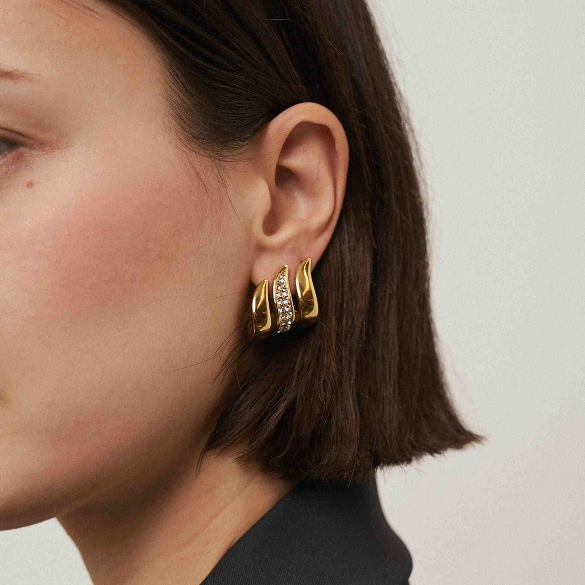 Girl Wearing 18k Gold Plated Crystal Detailed Flame Stud Earrings having Fire Flame Silhouette with Zircons. Shop at Mithra and Co.