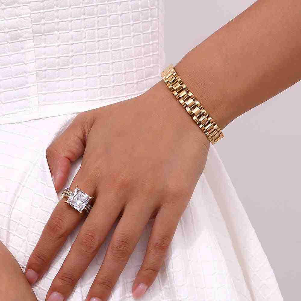 Girl wearing Waterproof 18k Gold plated michael bold bracelet and aura zircon ring posing in a white dress.