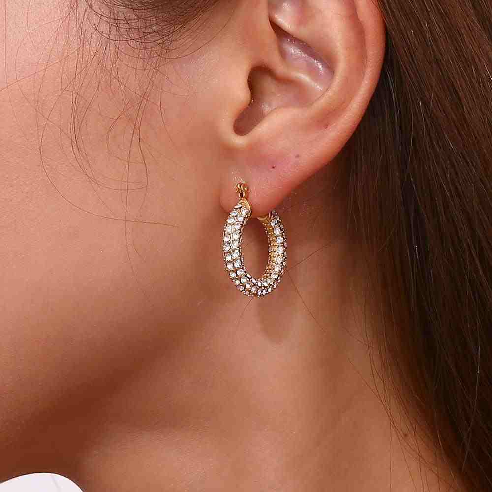 Closeup of a woman's left ear wearing Arlo medium hoops with pave Zircons 3 Row set sparkle.