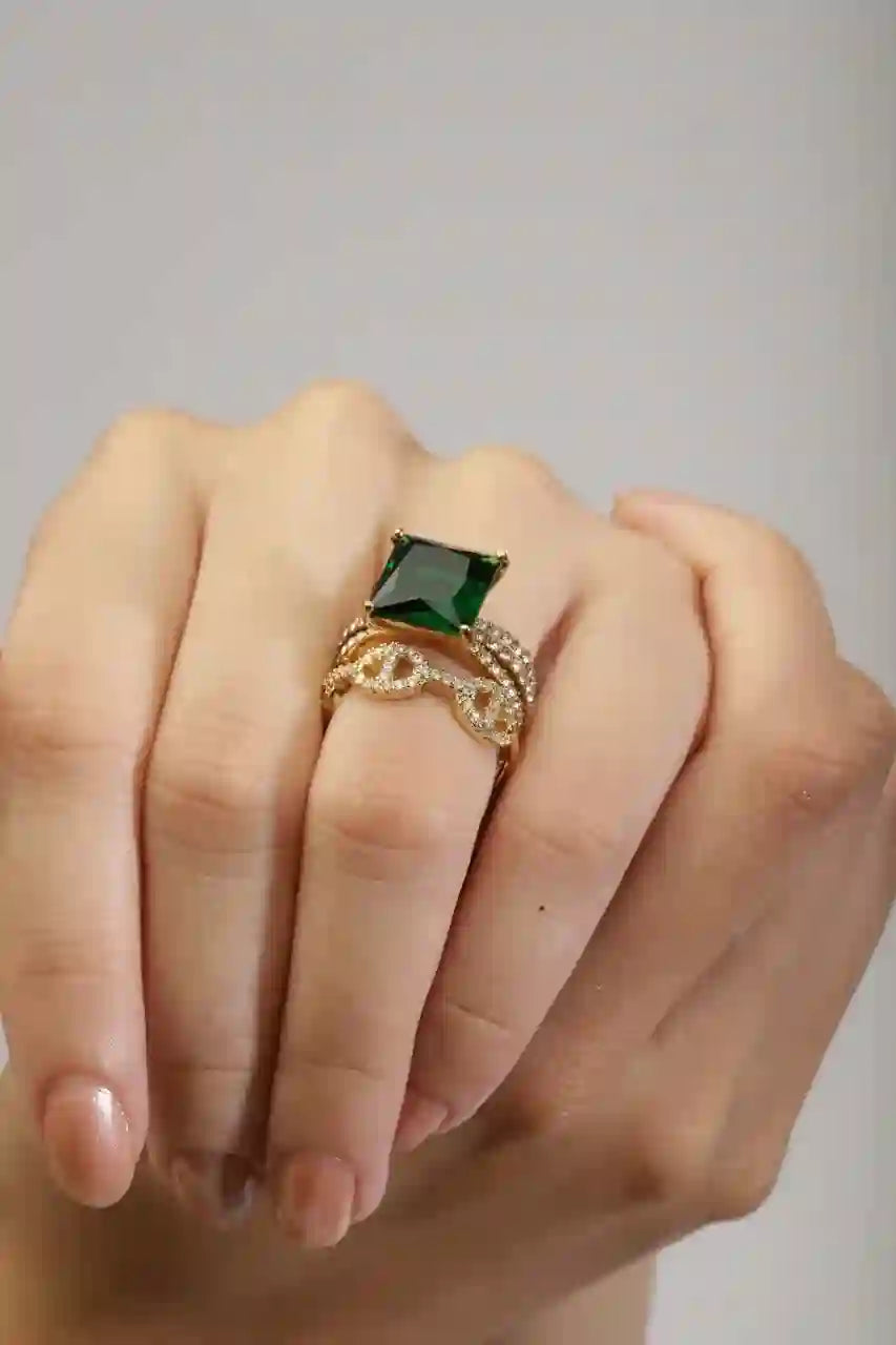 Closeup of hands wearing Aura Ring Square Emerald Stone Engagement Ring with Dior style ring. Shop at Mithra and Co.
