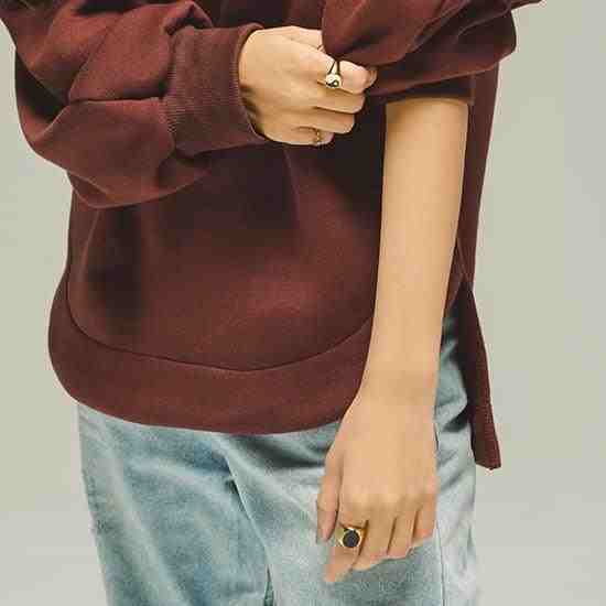 Girl in brown shirt and blue jeans, wearing 3 rings including ramsey signet black onyx ring, folding sleeve with one hand to reveal jewelry.
