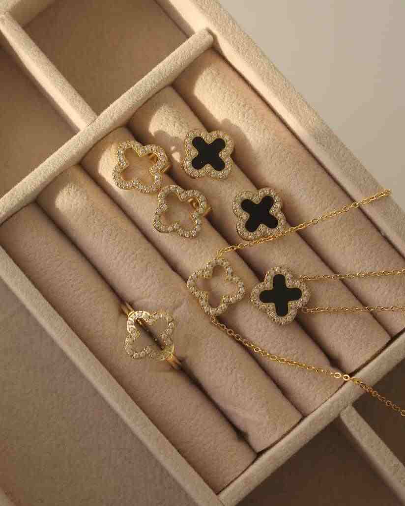 Box display containing Hollow Clover Studded ring, stud earrings, and necklace with 4 leaf Hollow Floral motifs bordered with zircons.