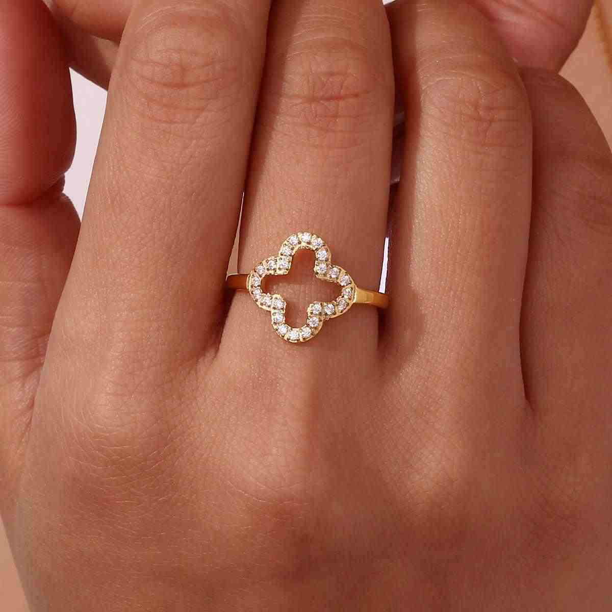 Closeup of Hand wearing Hollow Clover studded ring with an open work 4 leaf clover floral motif with bordering zircons.