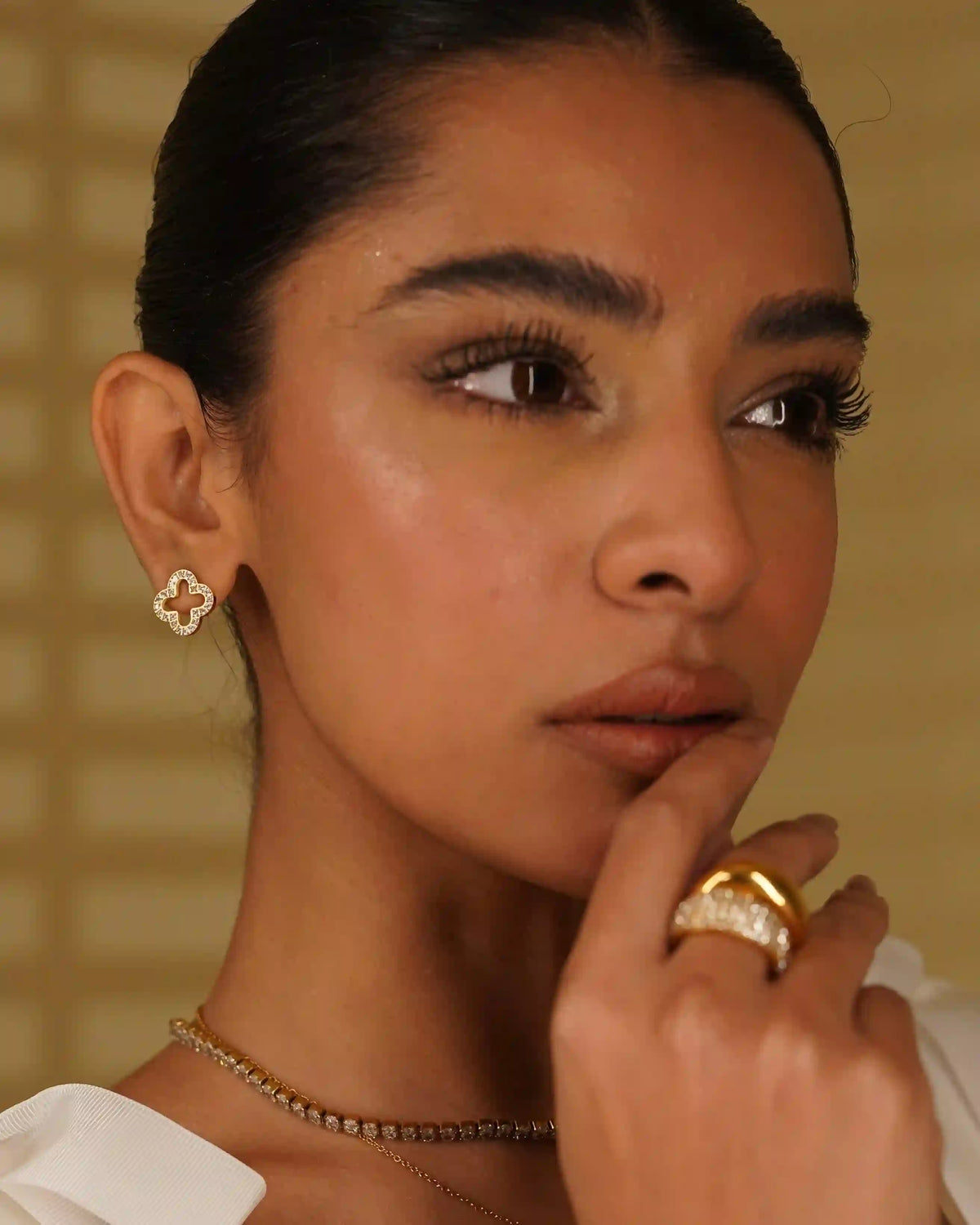 Closeup of a Woman wearing Linea necklace, Hollow clover studs and hollow clover necklace with domsley and studded domsley rings in middle finger.