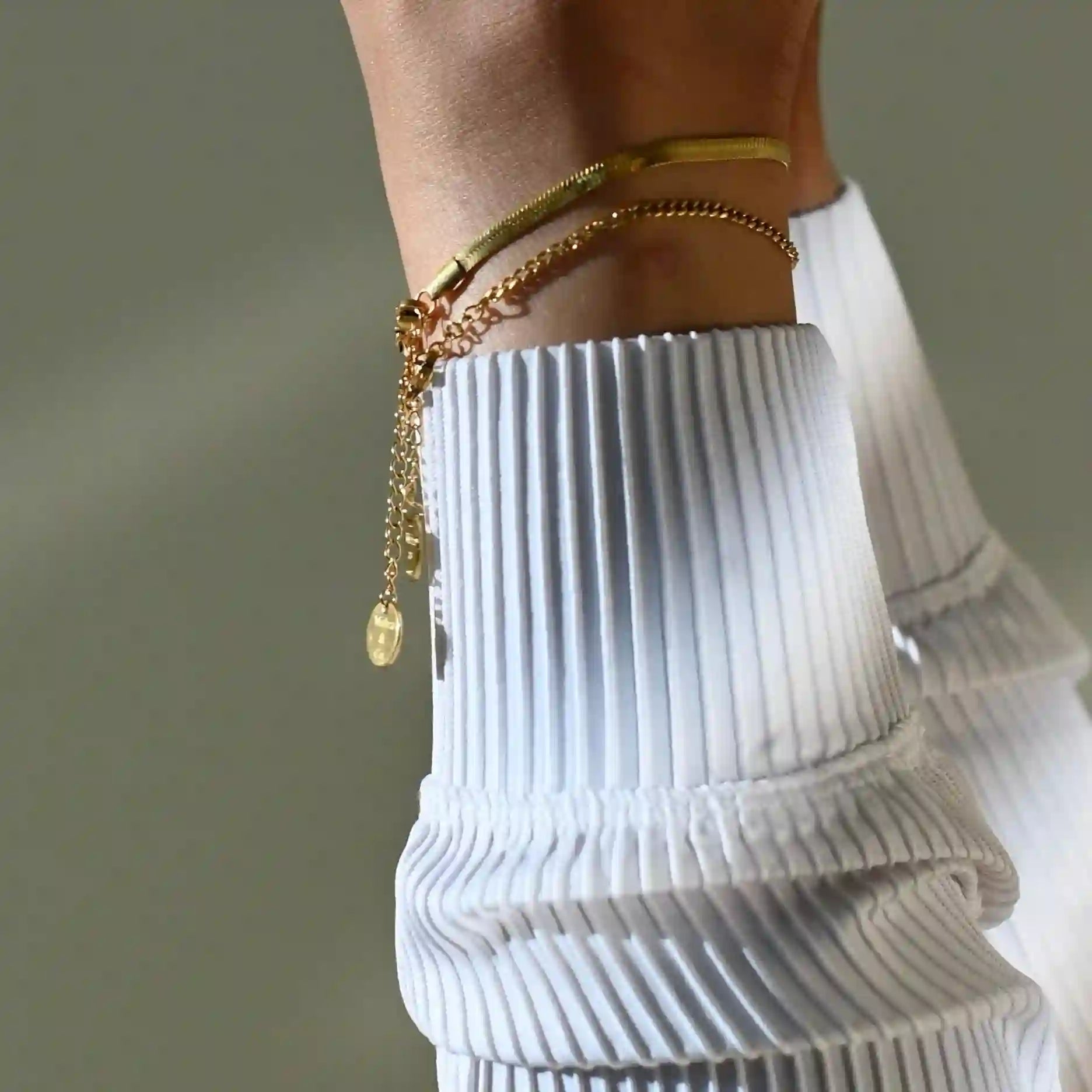 Woman wearing 18k Gold Plated double chain bracelets on wrist with white ribbed sleeve