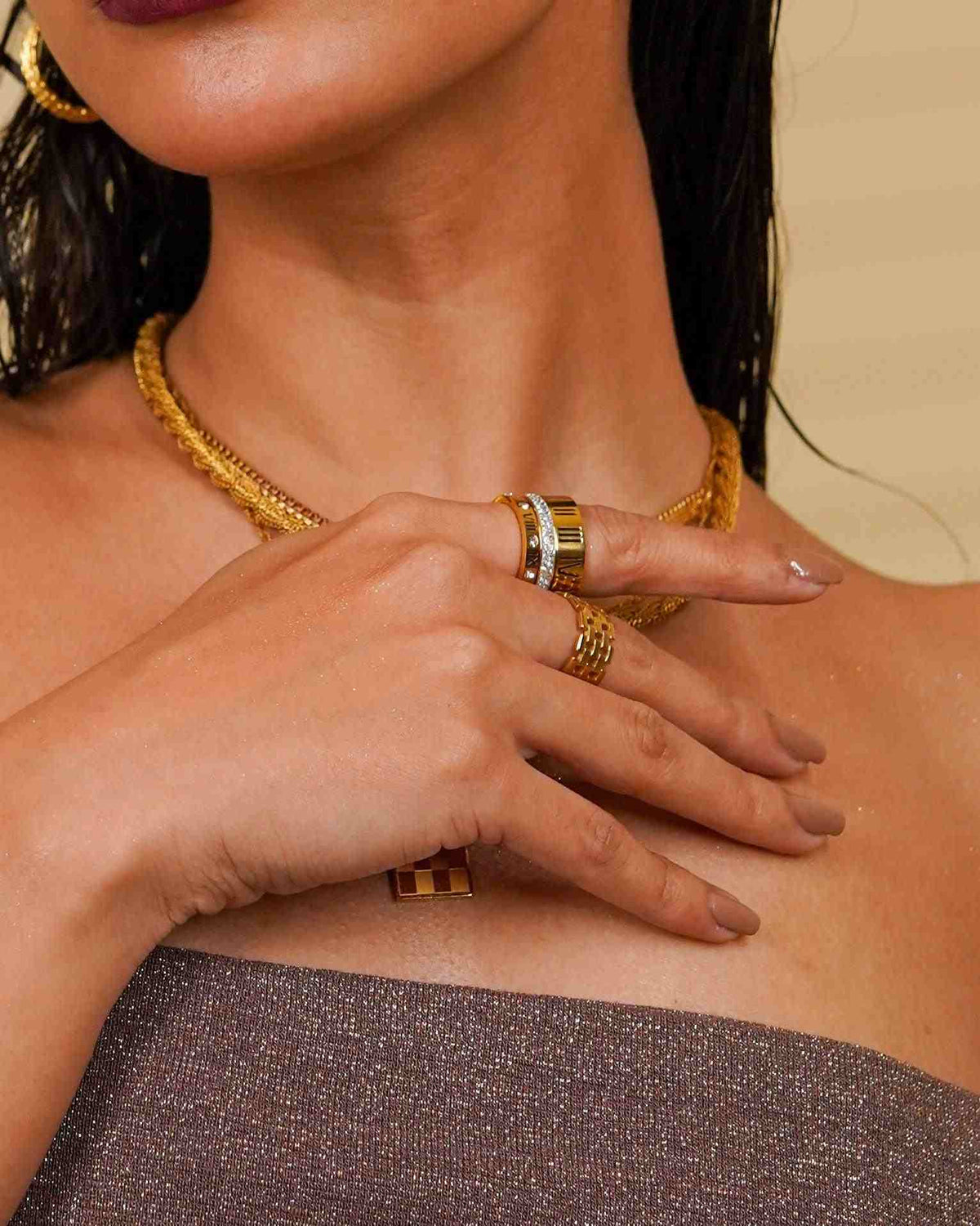 Close-up of a girl wearing gold plated necklaces, earrings, trilogy stacked ring and mesh ring.