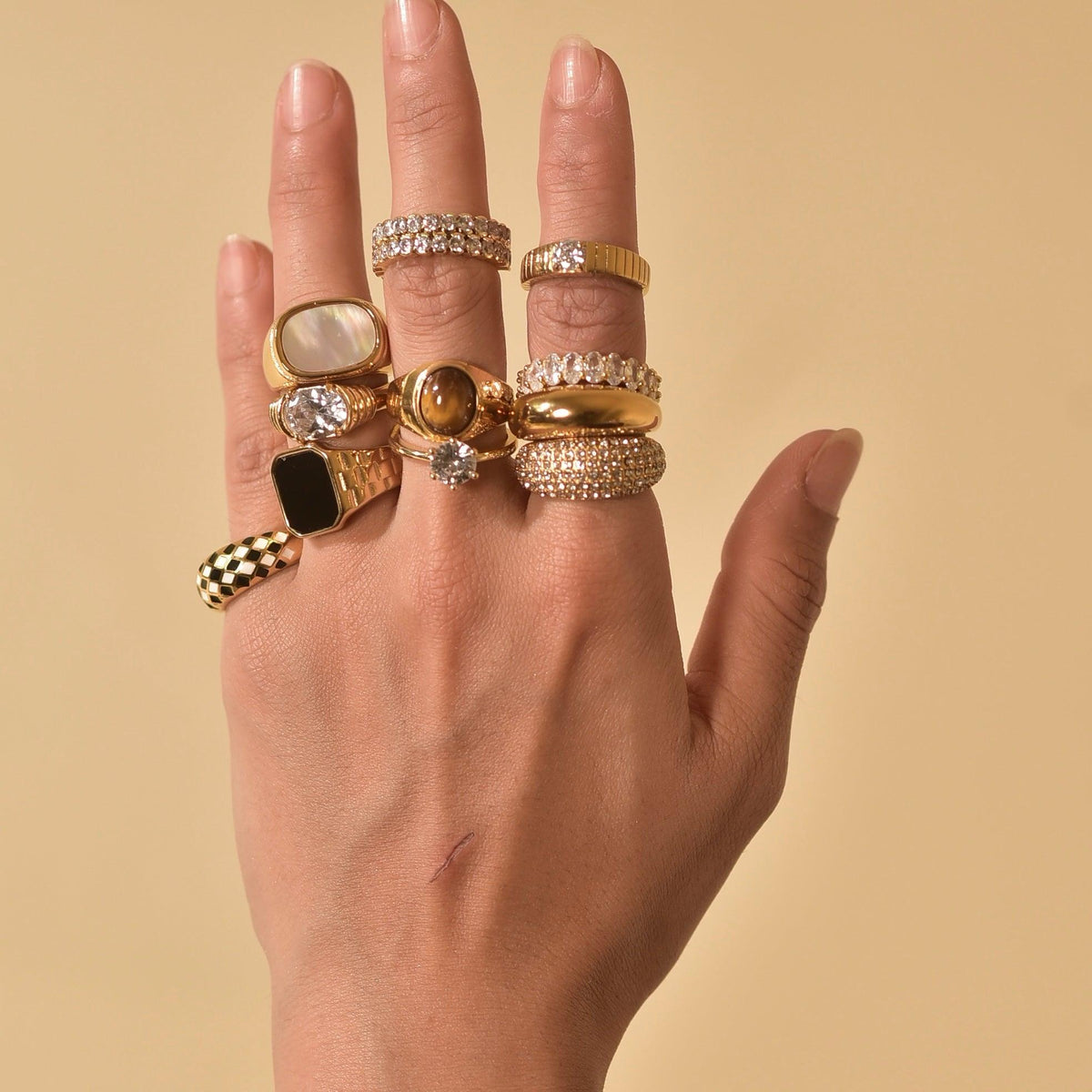 Hand wearing bowie ring including 9 other 18k Gold Plated Rings Stacking Heavily.